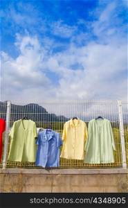 fashion outdoor market with clothes hanging from fence under blue sky
