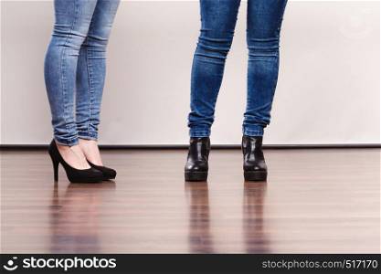 Fashion outfit. Female legs in denim pants and black high heels shoes. Female legs in denim pants heeled shoes