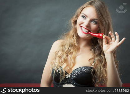 Fashion, people concept. Young lady with nice teeth. Woman is putting red hot chili pepper in her mouth.. Woman with chili pepper in mounth.