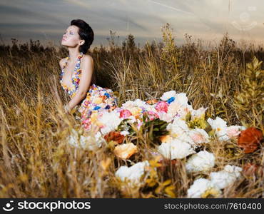 Fashion photo of beautiful lady in dress of flowers. Beautiful woman pose outdors.