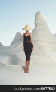 Fashion photo of beautiful lady in hat in an unusual landscape