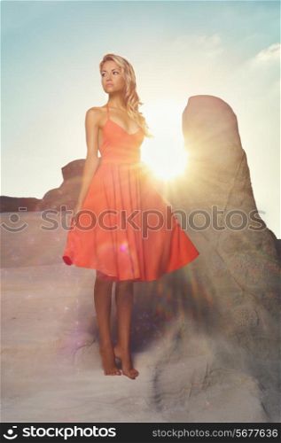 Fashion photo of beautiful lady in red dress in an unusual landscape