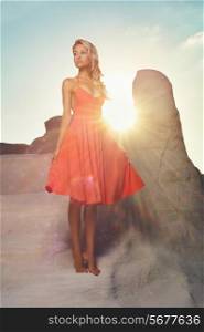 Fashion photo of beautiful lady in red dress in an unusual landscape