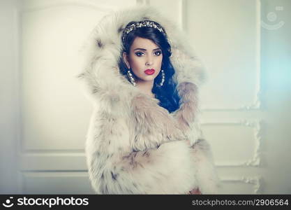 Fashion photo of beautiful young lady in a luxurious fur coat