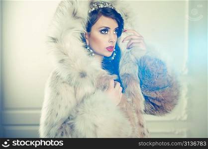 Fashion photo of beautiful young lady in a luxurious fur coat
