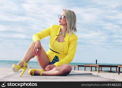 Fashion photo of sexy blonde posing on the beach. Outdoor shot. Photo toned style Instagram filters