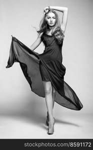 Fashion photo of young magnificent woman in black dress. Studio black and white photo