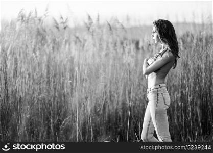 Fashion photograph of young sensual woman in jeans, in nature