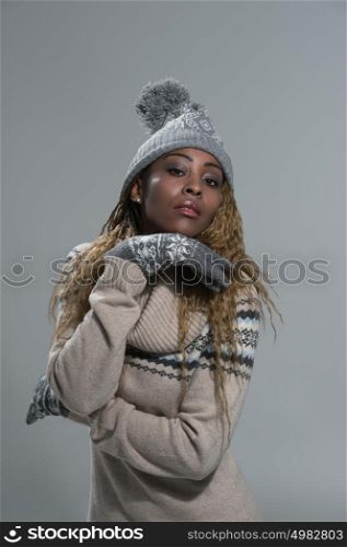 Fashion picture of beautiful smiling african woman wearing a woolen sweater and knitted hat with pompom