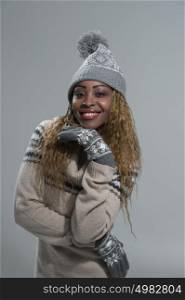 Fashion picture of beautiful smiling african woman wearing a woolen sweater and knitted hat with pompom
