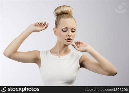 fashion portarit of a young pretty girl with hairstyle and a white dress looking down
