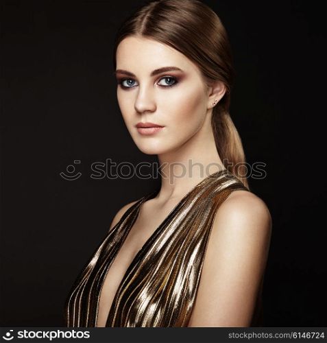 Fashion portrain of young beautiful woman in gold dress. Brunette glamour lady with perfect make up and hairstyle