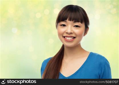 fashion, portrait and people concept - happy smiling young asian woman over green background with lights. happy smiling young asian woman