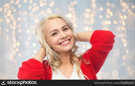 fashion, portrait and people concept - happy smiling young woman in red cardigan over holidays lights background. happy smiling young woman in red cardigan