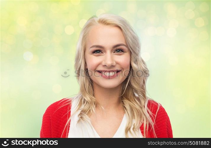 fashion, portrait and people concept - happy smiling young woman in red cardigan over green background with lights. happy smiling young woman in red cardigan