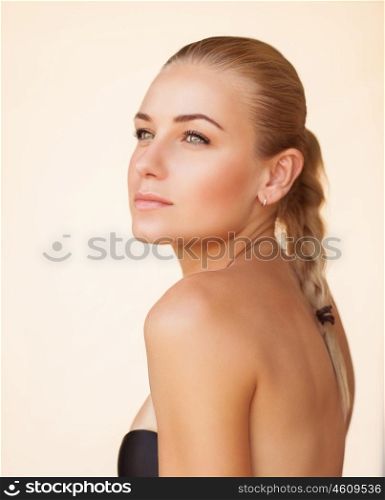 Fashion portrait of a beautiful blond girl with bare makeup over beige background, natural beauty of a woman face with a healthy skin, sensual look