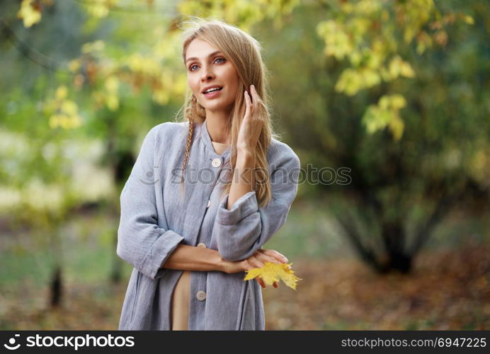 Fashion portrait of beautiful blonde woman in stylish clothes in autumn park.. Fashion portrait of beautiful blonde woman in stylish clothes in autumn park