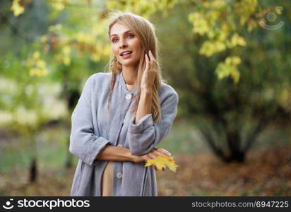 Fashion portrait of beautiful blonde woman in stylish clothes in autumn park.. Fashion portrait of beautiful blonde woman in stylish clothes in autumn park