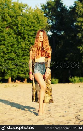 Fashion portrait of beautiful hippie young woman wearing boho chic clothes, chiffon cardigan and boho chic style bijouterie. Blonde haired woman dressed in bohemian style at the beach.