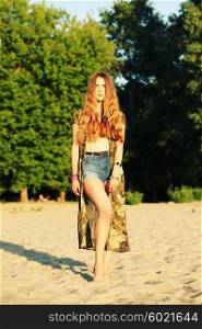 Fashion portrait of beautiful hippie young woman wearing boho chic clothes, chiffon cardigan and boho chic style bijouterie. Blonde haired woman dressed in bohemian style at the beach.