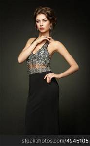 Fashion portrait of beautiful woman in elegant black evening dress. Girl with elegant hairstyle and jewelry