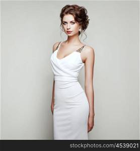 Fashion portrait of beautiful woman in elegant white dress. Girl with elegant hairstyle and jewelry