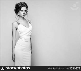 Fashion portrait of beautiful woman in elegant white dress. Girl with elegant hairstyle and jewelry. Black and White