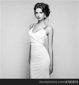 Fashion portrait of beautiful woman in elegant white dress. Girl with elegant hairstyle and jewelry. Black and White