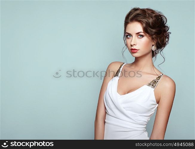 Fashion portrait of beautiful woman in elegant white evening dress. Girl with elegant hairstyle and jewelry