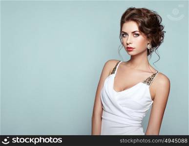 Fashion portrait of beautiful woman in elegant white evening dress. Girl with elegant hairstyle and jewelry