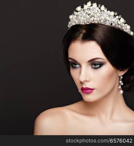 Fashion Portrait of Beautiful Woman with Tiara on head. Elegant Hairstyle. Perfect Make-Up and Jewelry. Red Lips