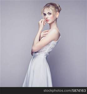 Fashion portrait of beautiful young woman with blond hair. Girl in white dress on white background