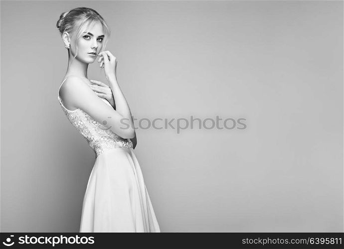Fashion portrait of Beautiful Young Woman with Blond Hair. Girl in white Dress on White Background. Black and White photo