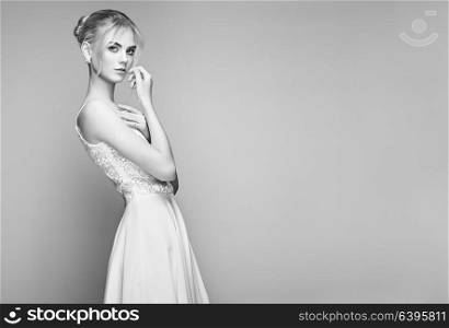 Fashion portrait of Beautiful Young Woman with Blond Hair. Girl in white Dress on White Background. Black and White photo
