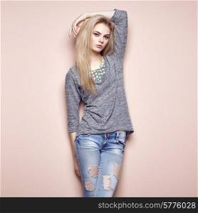 Fashion portrait of beautiful young woman with blond hair. Girl in blouse and jeans. Jewelry and hairstyle