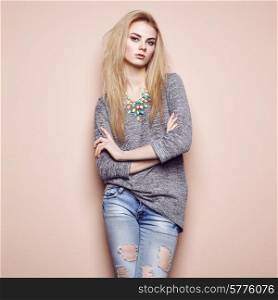Fashion portrait of beautiful young woman with blond hair. Girl in blouse and jeans. Jewelry and hairstyle