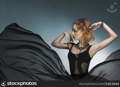 fashion portrait of bizarre dark lady with gothic style, strong make-up and rock accessories wearing and big veil flying skirt. Carnival look