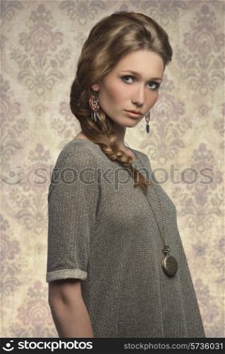fashion portrait of cute blonde girl with long braid hair-style, gray dress and stylish necklace &#xA;
