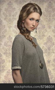 fashion portrait of cute blonde girl with long braid hair-style, gray dress and stylish necklace &#xA;