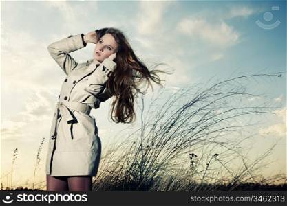 Fashion portrait of elegant woman in a raincoat on the nature