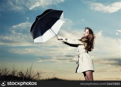 Fashion portrait of elegant woman in a raincoat on the nature. Woman with an umbrella