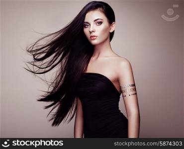 Fashion portrait of elegant woman with magnificent hair. Brunette girl. Perfect make-up. Girl in elegant dress. Flash tattoo gold
