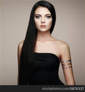 Fashion portrait of elegant woman with magnificent hair. Brunette girl. Perfect make-up. Girl in elegant dress. Flash tattoo gold