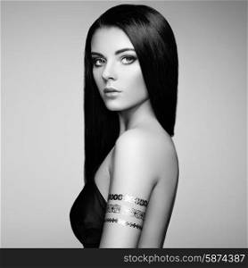 Fashion portrait of elegant woman with magnificent hair. Brunette girl. Perfect make-up. Girl in elegant dress. Flash tattoo gold. Black and white