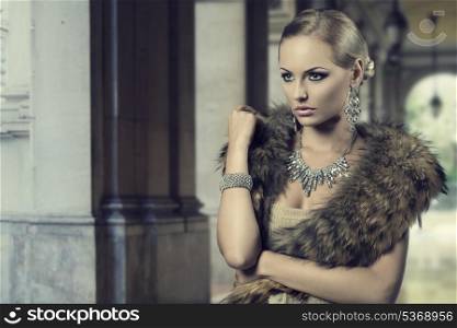 fashion portrait of luxury blonde girl posing with elegant hair-style, fur shawl and precious shiny jewellery. Cute make-up