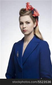 fashion portrait of pretty blonde girl with elegant style, wearing blue coat, feather shaped brooch and vintage foulard in the hair-style