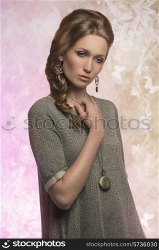 fashion portrait of trendy blonde lady with long braid hair-style, gray dress, stylish necklace and earrings