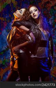 Fashion portrait of two rock girls posing on colorful background