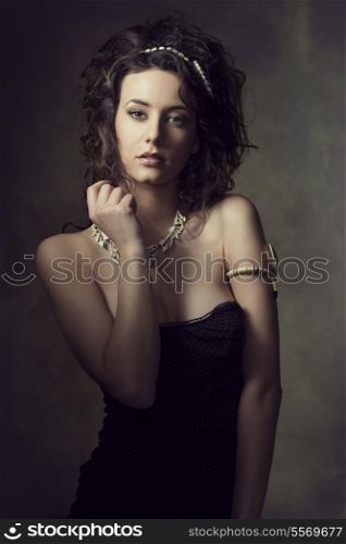 fashion portrait of very sensual brunette woman with curly hair-style, wearing creative jewels and sexy dress