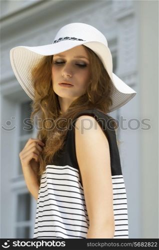 Fashion portrait of well dressed woman in summer hat on the street in sunny day. She has got nice, brown make up.